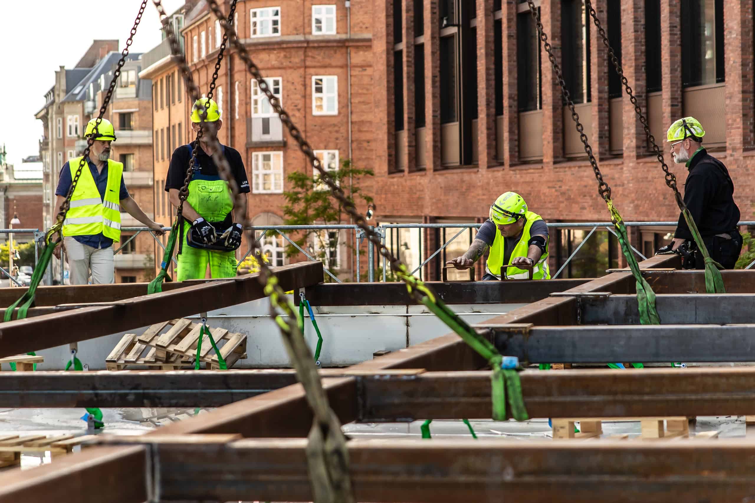 Site workers guiding a lifted metal structure in the installation gallery of Herfølge Kleinsmedie.